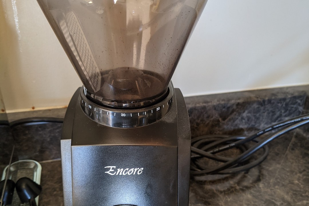 A conical burr coffee grinder with a numbered grind-adjustment collar showing the range from espresso to coarse settings