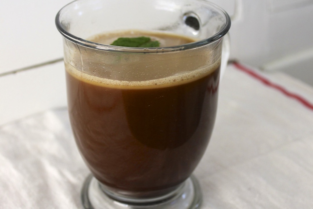 A glass mug of butter coffee with a layer of emulsified fat resting on the surface
