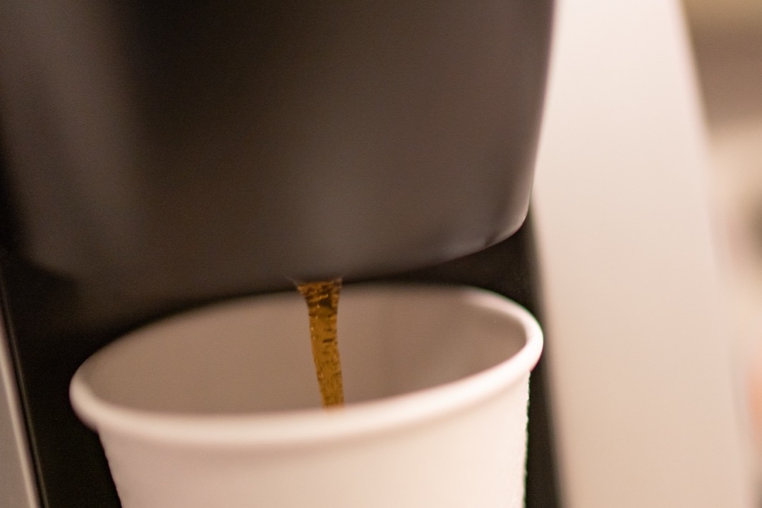 A single-serve coffee maker brewing one cup directly into a mug on a kitchen counter