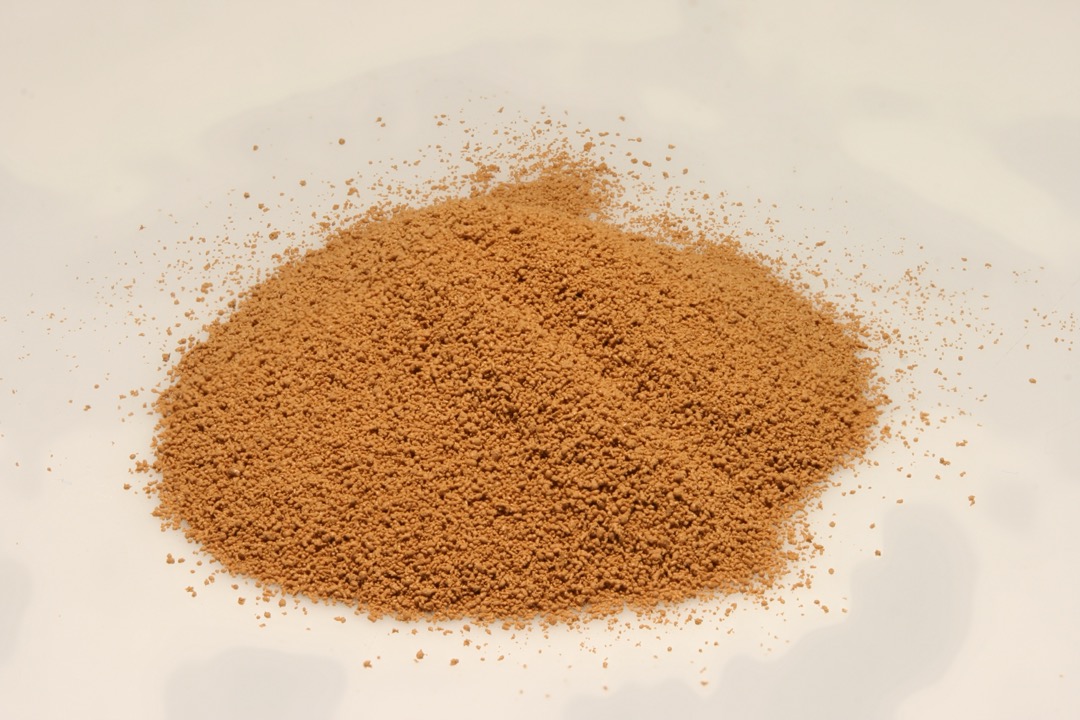 A mound of fine dark instant espresso powder on a white surface