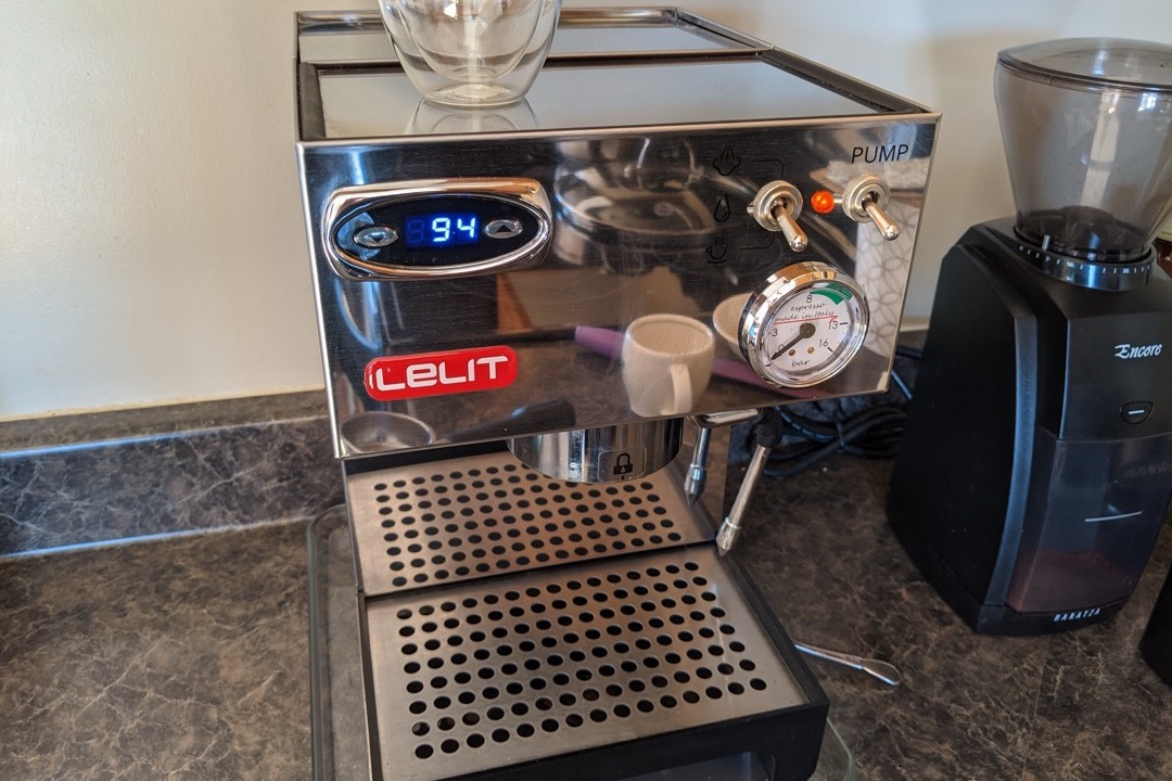 A semi-automatic home espresso machine with a pressure gauge and portafilter on a kitchen counter